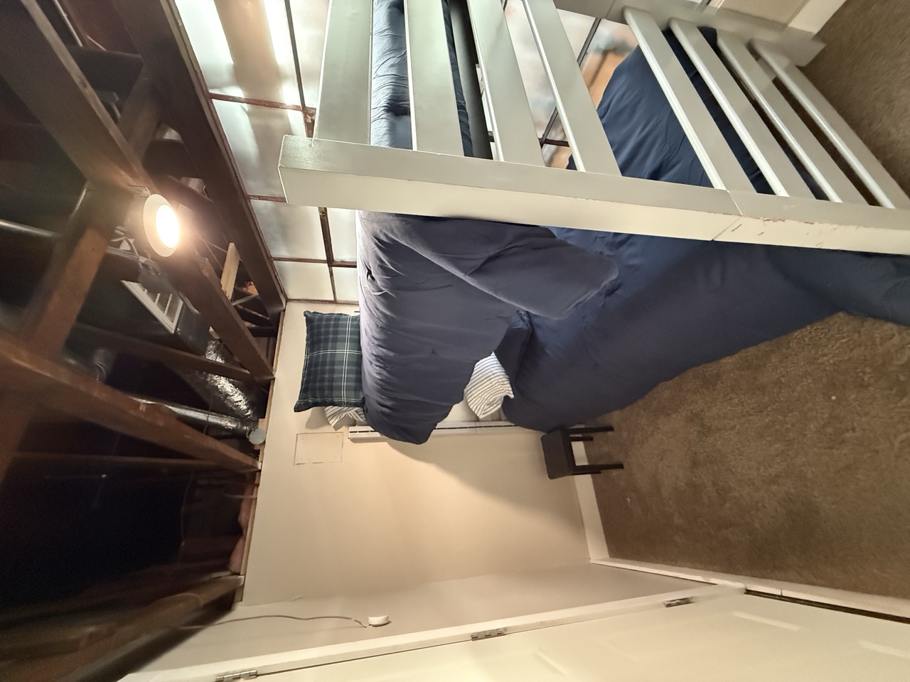 The second bunk room, bunks against bare brick with a lamp glowing between them.