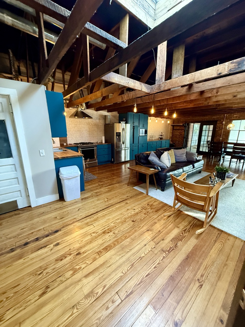 The living area under a skylight set into the timber roof, sofa and armchairs gathered on the wood floor.
