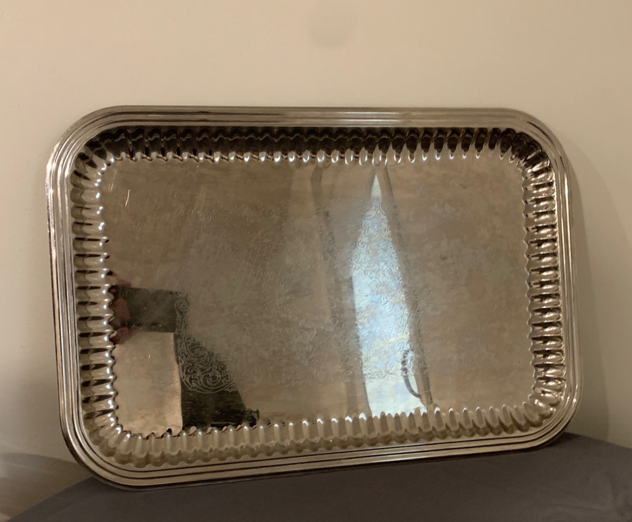 A rectangular silver serving tray with a fluted rim, stood on its edge.